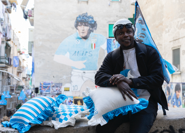 Maradonna, napoli, cushions. Paboy is holding cushions with a football theme. cushions are in the colours of the Napoli flag to celebarte their win